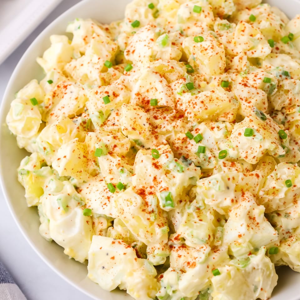 Creamy American potato salad with paprika and chives in a white bowl at The Potpourri House Restaurant.