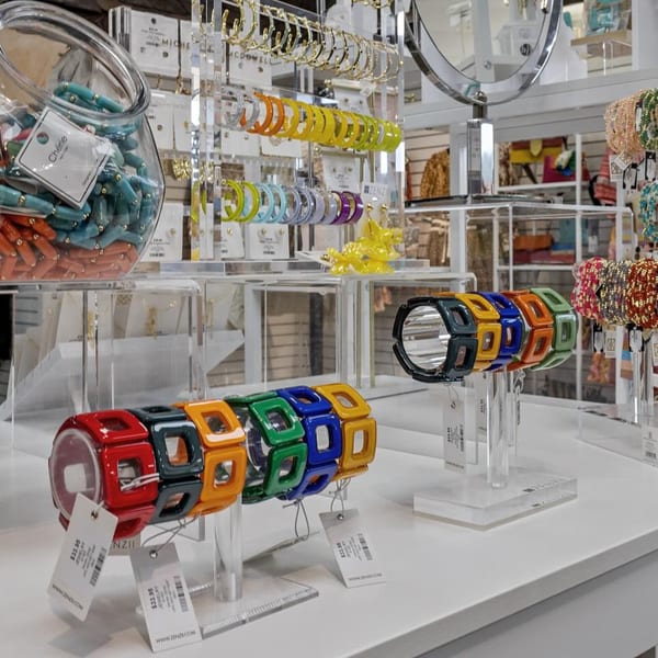 Colorful bracelets and earrings displayed on clear stands in a retail store.