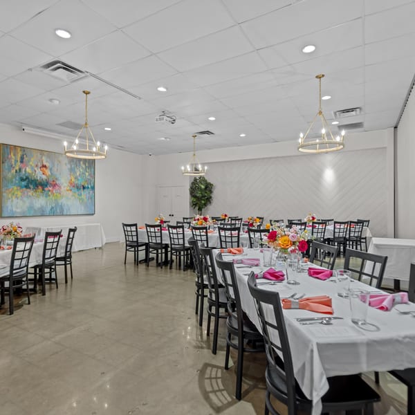 A large, brightly lit event room at The Potpourri House Restaurant with multiple tables set for dining.