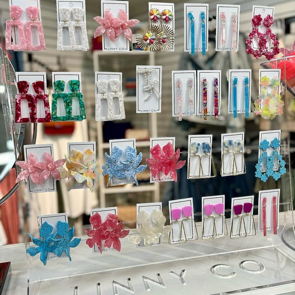 A display of colorful earrings in various shapes and sizes, including floral and geometric designs.